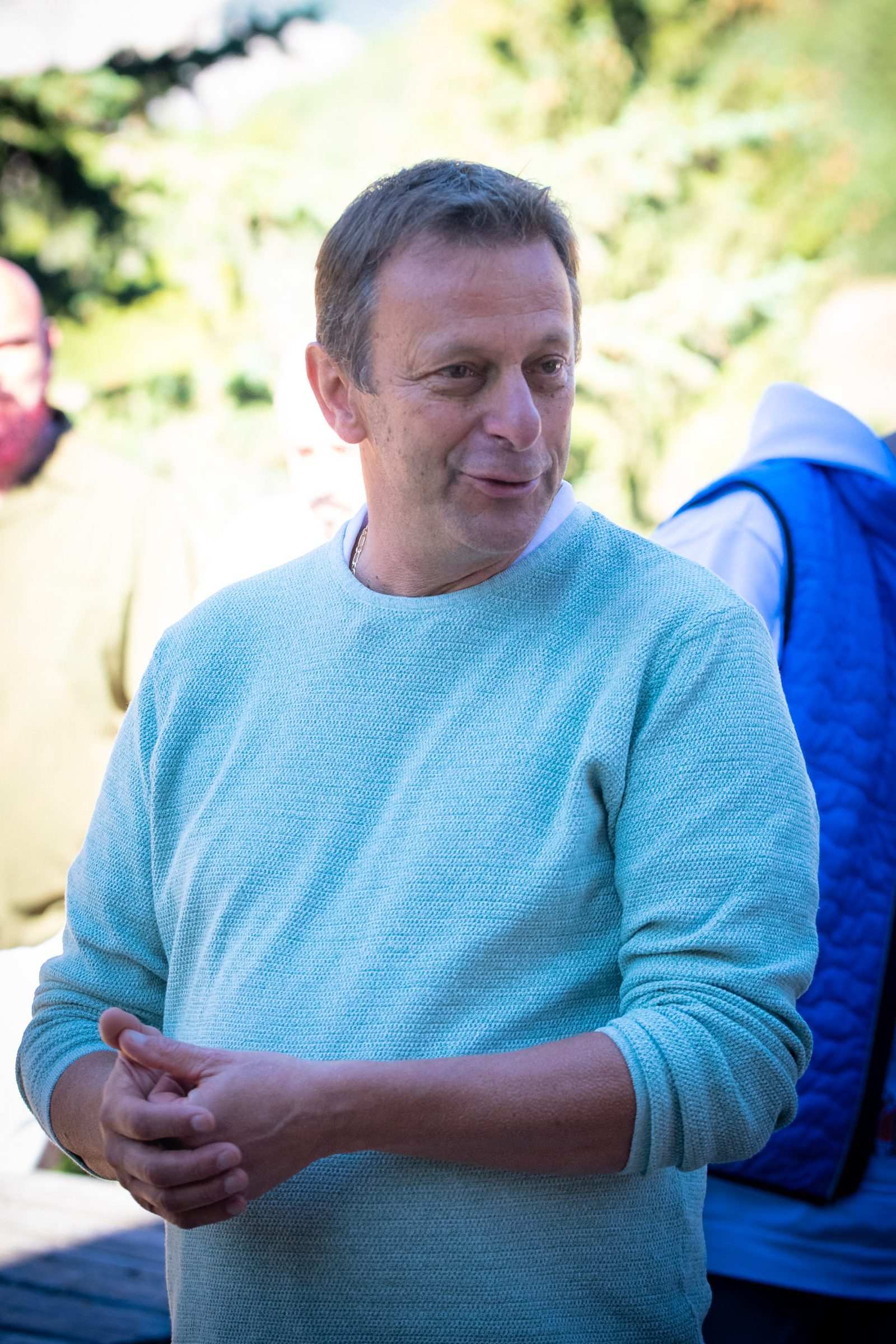 Un participant en pull bleu clair écoute les échanges