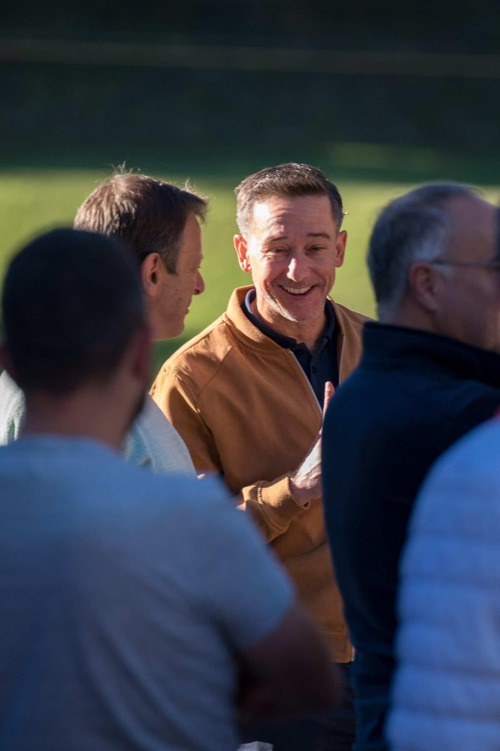 Échanges souriants entre participants, le green en arrière-plan