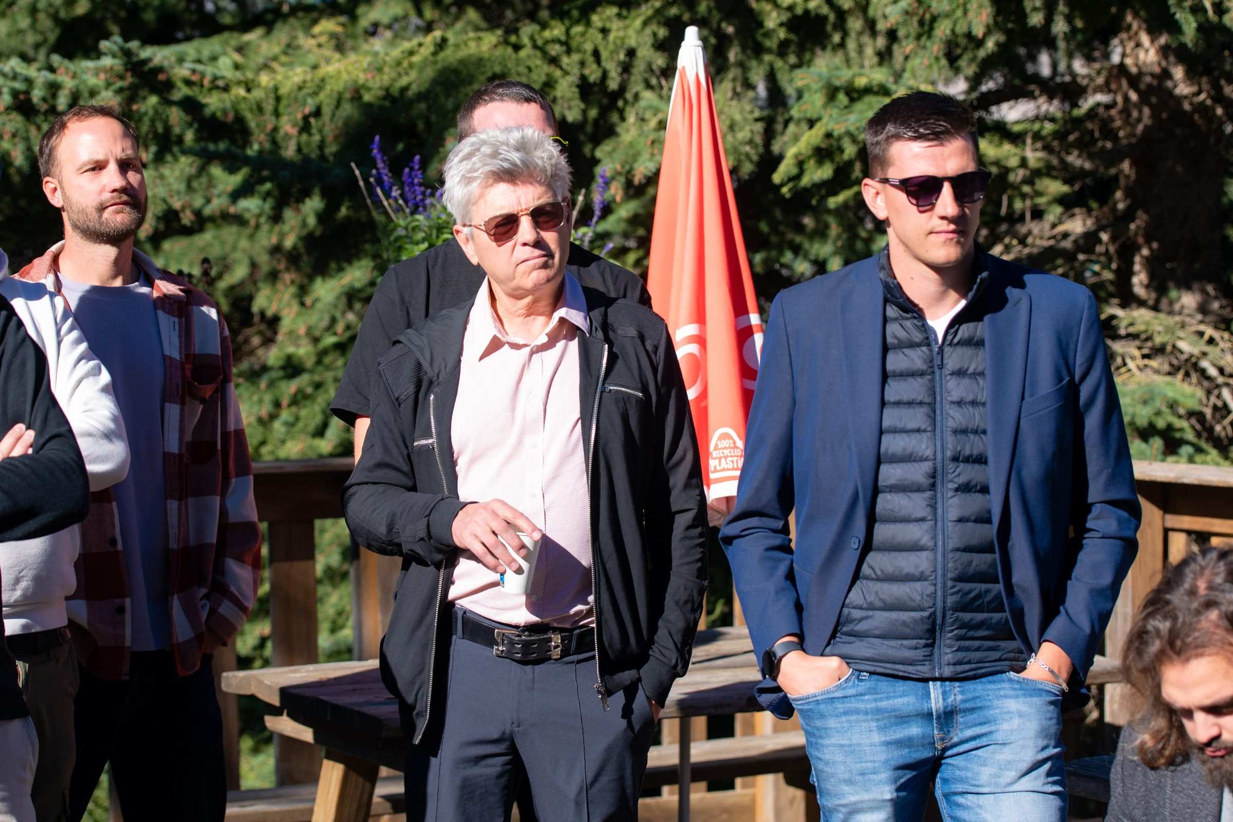 Trois participants debout devant le parasol du golf